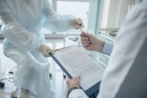 A doctor handing a clipboard to a patient to sign a consent form