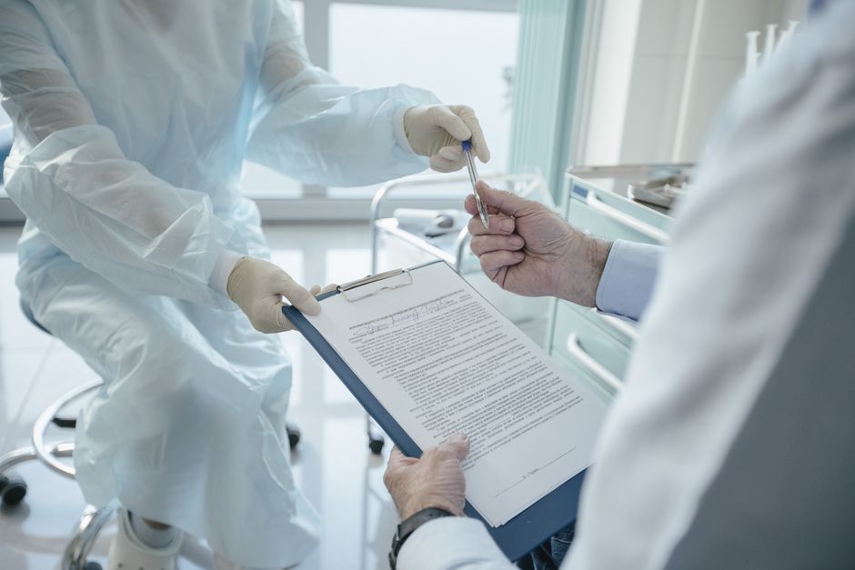A doctor handing a clipboard to a patient to sign a consent form