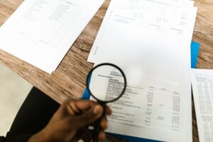 Hand using a magnifying glass to review financial documents