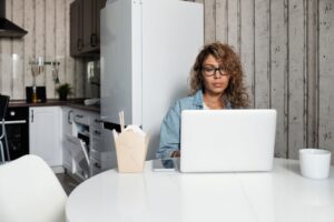 A woman using a laptop at her kitchen table at home