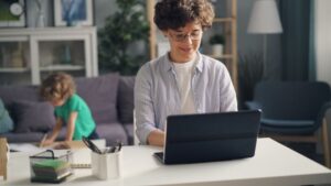 A mother working at a laptop at home while her child plays nearby