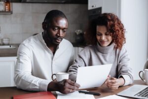 Two people reviewing paperwork together at a kitchen table at home