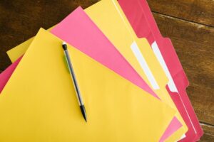 Document folders and a pen arranged on a wooden table