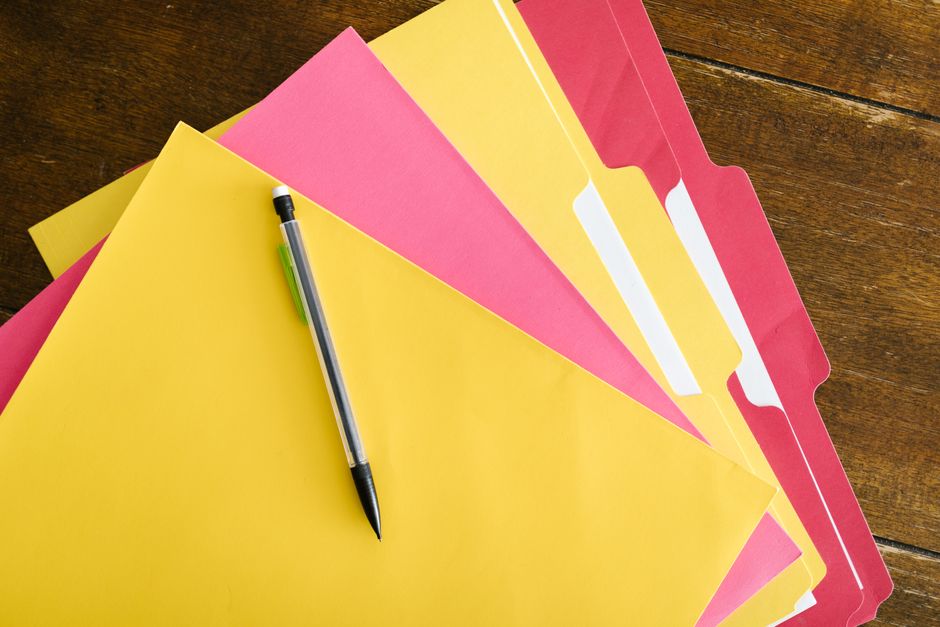 Document folders and a pen arranged on a wooden table